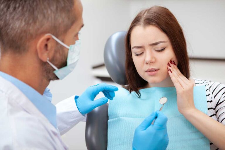 Person gently guiding floss between teeth in front of a bathroom mirror.