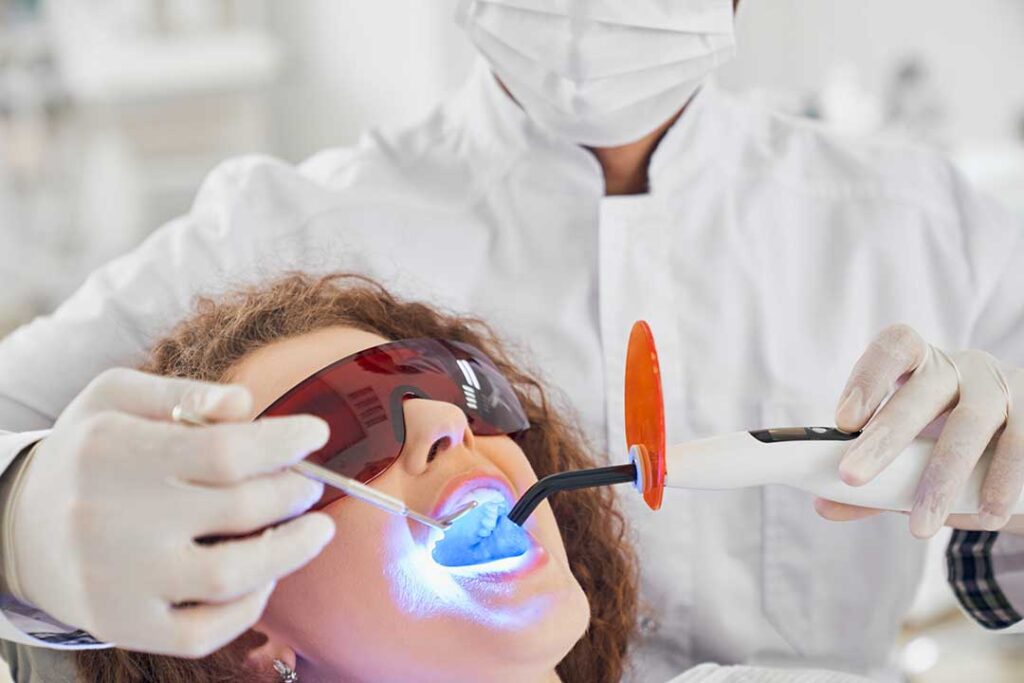 Person gently brushing sensitive teeth with a soft toothbrush beside a bathroom sink.