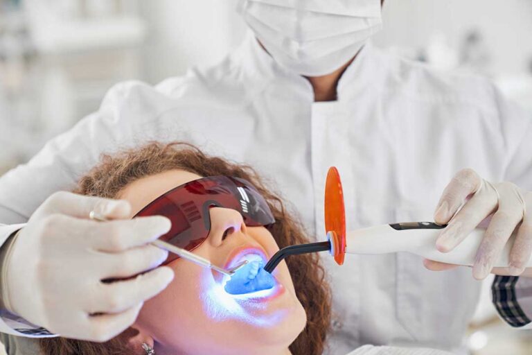 Person gently brushing sensitive teeth with a soft toothbrush beside a bathroom sink.